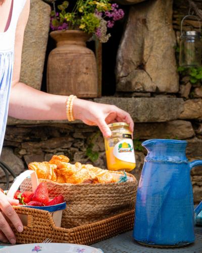 Eine Frau hält ein Glas Orangensaft neben einem Obstkorb. in der Unterkunft L'appart du Mas de la Costete Mons-Olargues-Caroux in Mons