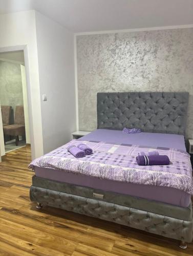 a bedroom with a bed with purple sheets and purple blankets at Apartmani AX in Pančevo