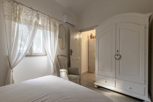 a white bedroom with a bed and a window at Casa Lilliosa in San Pasquale