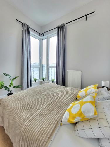 Un dormitorio con una cama grande con almohadas amarillas y blancas. en Ursus Premium Apartments, en Varsovia