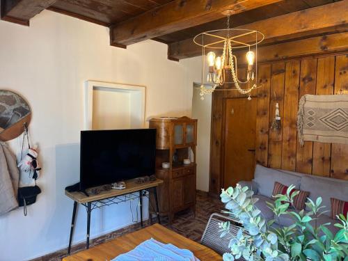 ein Wohnzimmer mit Fernseher und Kronleuchter in der Unterkunft Cabaña para 4 personas, zona centro, vista al Rio Aluminé in Aluminé