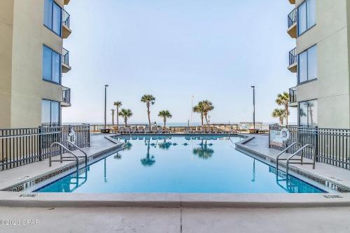 a large swimming pool with palm trees and buildings at Steps to the beach and amazing views! in Panama City Beach