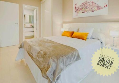 a white bed with orange pillows in a bedroom at Lujoso Golden Sunset in Oropesa del Mar