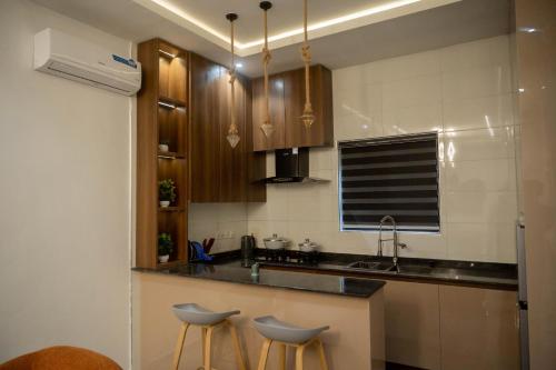 a kitchen with wooden cabinets and a sink and stools at Awka Luxury One Bed in Awka