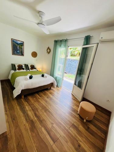 a bedroom with a bed and a sliding glass door at Le Calouni entre mer et volcan in Sainte-Rose