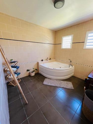 a large bathroom with a tub and a tile floor at Le Calouni entre mer et volcan in Sainte-Rose