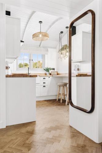 a kitchen with white cabinets and a large mirror at The Grove- Nestled by the green in Binsted