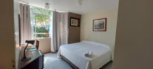a hotel room with a bed and a window at Flamboyant Hotel in Barra Velha