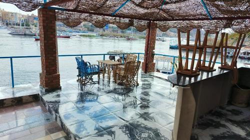 a patio with chairs and tables on the water at Awi Guest House in Aswan