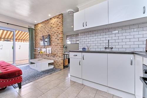 a kitchen with white cabinets and a brick wall at Clear Skies in Kempton Park