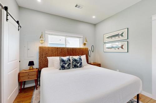 a bedroom with a large white bed and a window at Modern Steps to Beach Shared Pool & Playground in Caplen