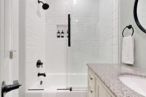 a white bathroom with a shower and a sink at Modern Steps to Beach Shared Pool & Playground in Caplen