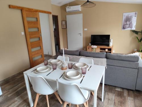 une table de salle à manger blanche avec des chaises blanches et un canapé dans l'établissement Petite maison de charme, à LʼIsle-sur-la-Sorgue
