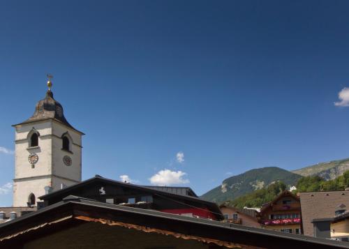 a clock tower on a building with mountains in the background at Hotel Weisser Hirsch in St. Wolfgang