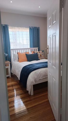 a bedroom with a large bed with blue curtains at 27 on Brunswick in Gqeberha