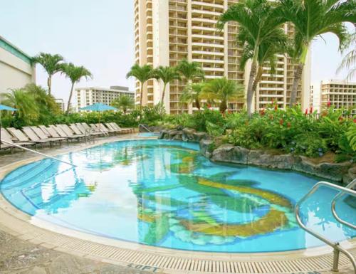 a large swimming pool with palm trees and a building at Hilton Grand Vacations Club at Hilton Hawaiian Village in Honolulu