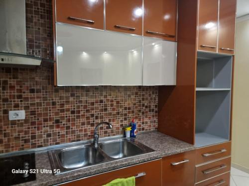 a kitchen with a stainless steel sink and brown cabinets at Luxury Two Bedrooms and two balcony beachfront apartment in Vlorë