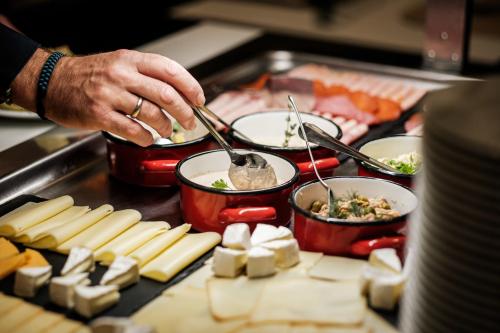 uma pessoa cozinhando comida em panelas na grelha em Corso Hotel Pécs em Pécs