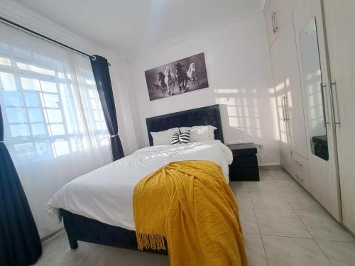 a bedroom with a bed with a yellow blanket on it at Del's Homes -Ruiru in Ruiru