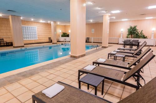 a hotel pool with tables and chairs next to a swimming pool at Holiday Inn Portland-By the Bay by IHG in Portland