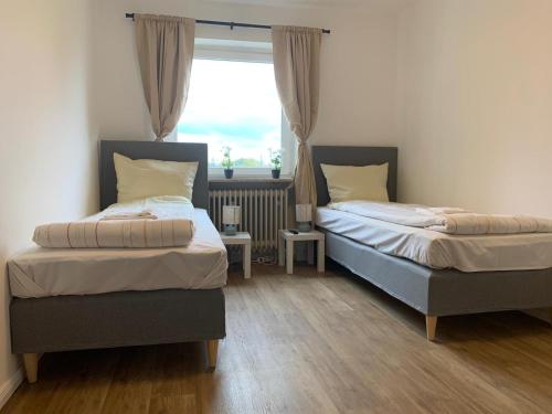 two beds in a room with a window at Lichtdurchflutetes City-Apartment im Herzen der Stadt in Neumünster