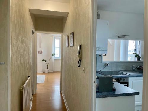 a kitchen with white cabinets and a wooden floor at Appartement paisible hyper centre in Vichy
