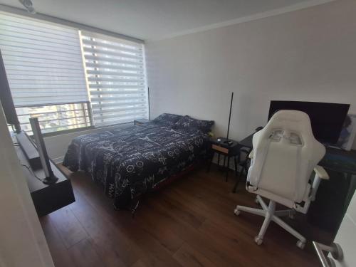 a bedroom with a bed and a chair next to a window at Departamento centro Viña del Mar in Viña del Mar