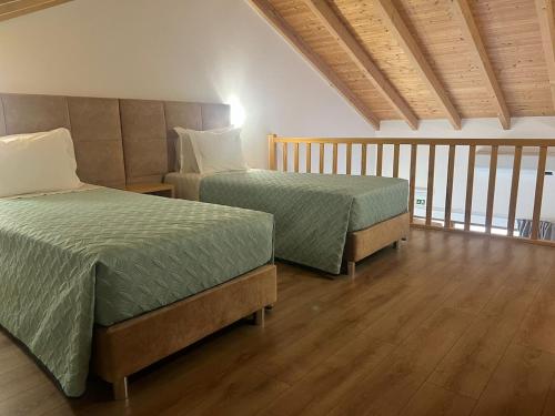 two beds in a room with wooden floors at Vila Lira in Aljezur