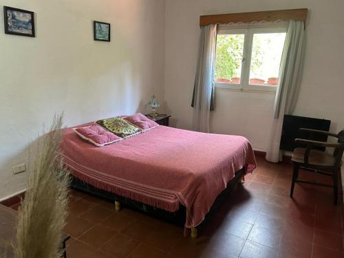 a bedroom with a bed with pink sheets and a window at depto de montaña con pileta in La Cumbre