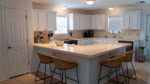 une cuisine avec des placards blancs et un îlot avec des tabourets de bar dans l'établissement Upscale & Spacious Home Renovated Pool, à South Padre Island