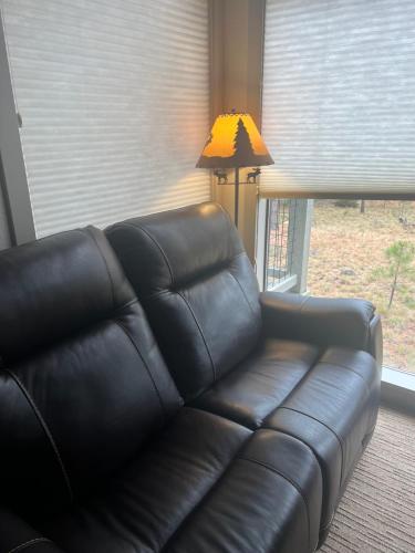 a black leather couch in a living room with a lamp at Great Kitchen, AC, SHARC Access, Hot Tub, Bring Pet! in Sunriver