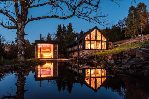 a house on a hill with a reflection in the water at Chata Pytlorka Beskydy offgrid wellness in Zahŭří