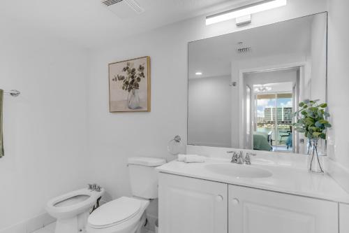 ein Badezimmer mit Toilette, Waschbecken und Spiegel in der Unterkunft Waterview Luxury 2-Bedroom Condo Sunny Isles Beach in Sunny Isles Beach