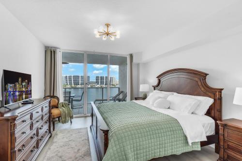 ein Schlafzimmer mit einem Bett mit einer grünen Decke und einem Fenster in der Unterkunft Waterview Luxury 2-Bedroom Condo Sunny Isles Beach in Sunny Isles Beach