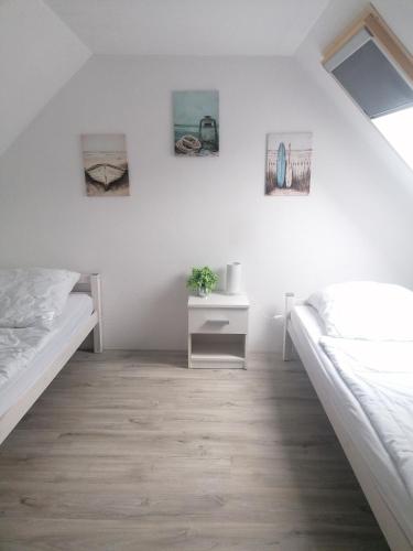 a white bedroom with two beds and a nightstand at Käpt'n Brandt in Osteel