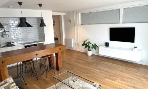 a living room with a table and a flat screen tv at Spacious Industrial style Apartment in London