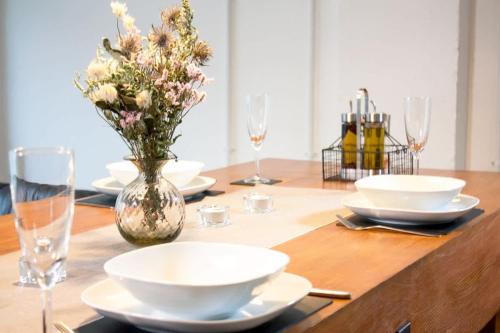 a table with plates and glasses and a vase with flowers at Spacious Industrial style Apartment in London