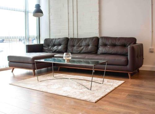 a living room with a leather couch and a glass table at Spacious Industrial style Apartment in London
