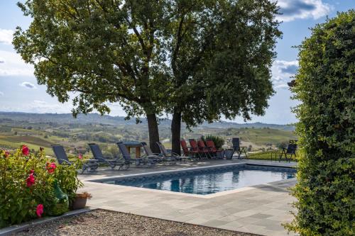 a swimming pool with chairs and a tree at Casa Nizza D'Oro in Castelnuovo