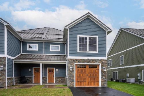 a house with grey siding and orange doors at Village Townhouse Walk to Shops Garage in Ellicottville