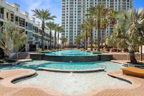 a large swimming pool with palm trees and buildings at Prestigious Luxury Beach & Bay Patios XL Size in South Padre Island