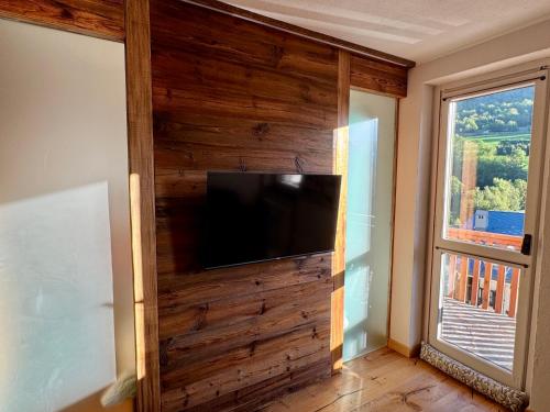 a living room with a wooden wall with a flat screen tv at Nido Alpino - Vista Montagne, Ski e Relax Terme a 150m in Pré-Saint-Didier