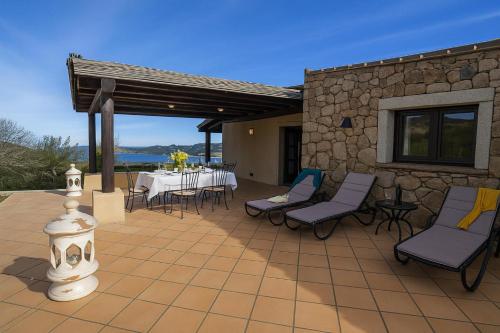 Un patio con mesa y sillas y un muro de piedra. en Villa Sul Golfo, en Cannigione