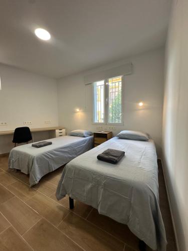ein Schlafzimmer mit zwei Betten und einem Fenster in der Unterkunft Guesthouse Cervantes - Rooms cerca del centro de Granada in Granada