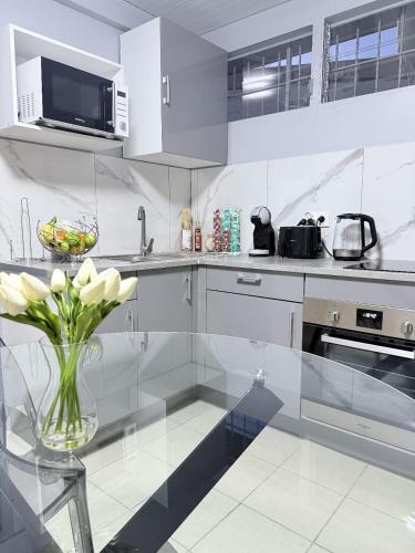 a white kitchen with a vase with flowers in it at Smylie home in Fort-de-France