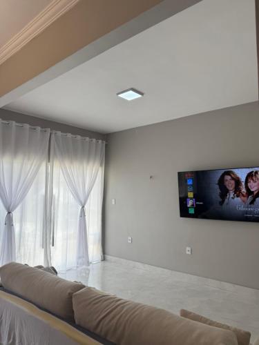 a living room with a couch and a tv on the wall at Alugo Casa COP30 em Belém no distrito de icoaraci in Belém