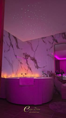 a purple bathroom with a tub and a mirror at Carpe Diem Spa Apartman in Teslić