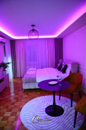 a room with a bed and a table with a purple ceiling at Carpe Diem Spa Apartman in Teslić