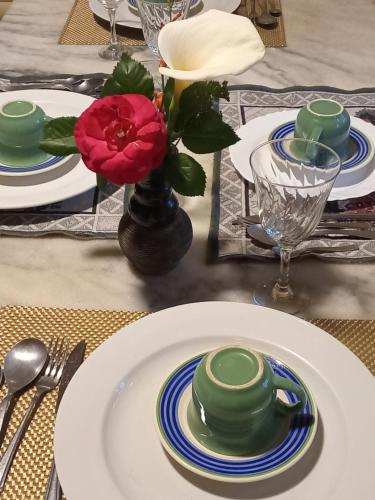 una mesa con platos y una flor roja en un jarrón en Chalé alpino em canela rs todo mobiliado com cozinha lareira split Wi-Fi 2 quartos perto do centro, en Canela