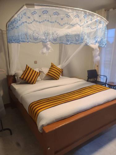 a bedroom with a canopy bed with striped pillows at Sqore Lounge in Gulu